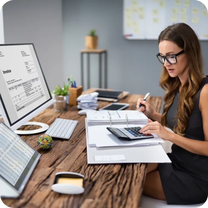 Woman working at a desk with a computer and calculator.