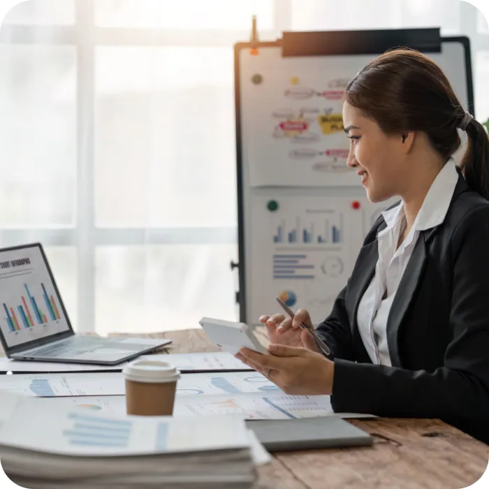 Professional woman at desk reviewing charts on laptop.