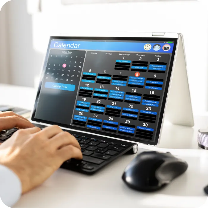Person typing on a computer displaying a calendar.