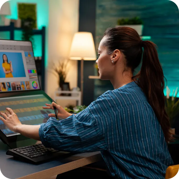 Woman editing on a large touchscreen computer in a cozy, well-lit room.
