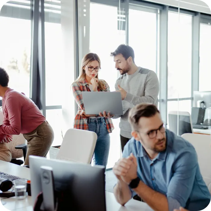Office scene with people collaborating and discussing work.