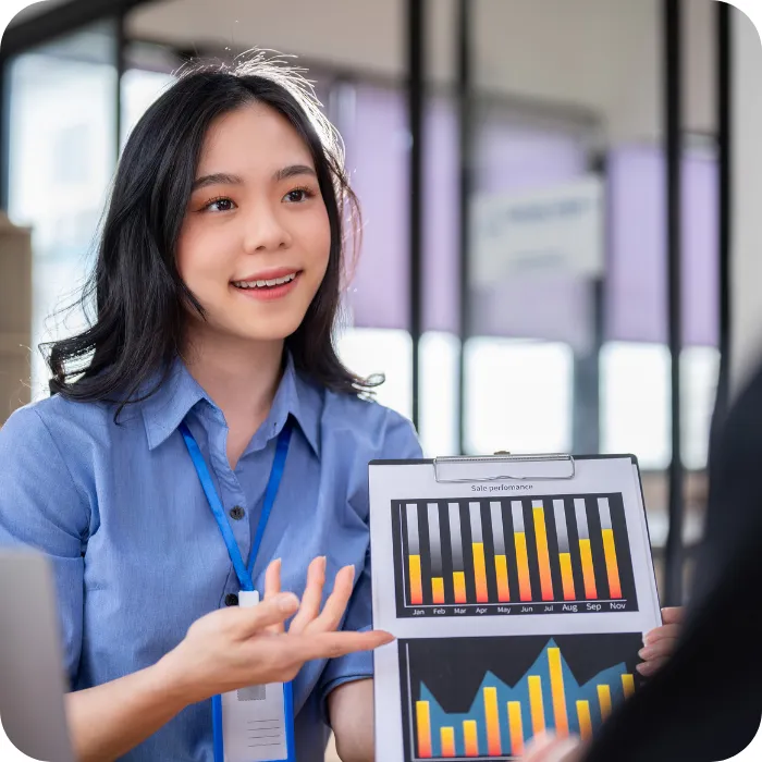 Young woman presenting colorful graphs in a bright office setting.