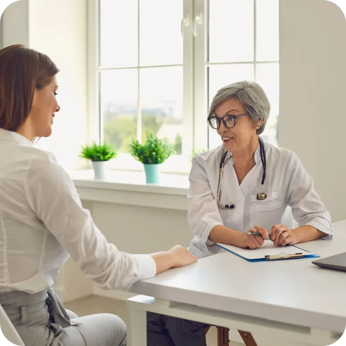 Doctor and patient talking at a sunny office desk.