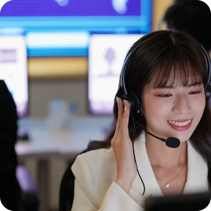Smiling woman in a call center, wearing a headset, in a bright office.