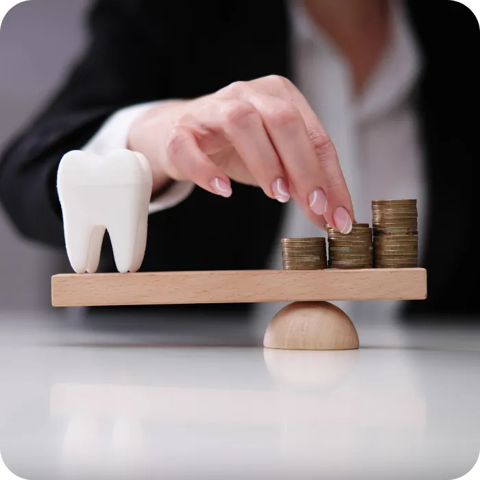 Tooth and stacked coins on a balance beam, hand adjusting coins.
