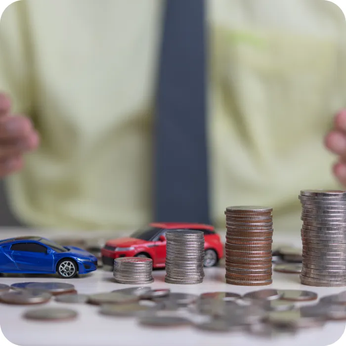 Toy cars beside stacks of coins on a table.