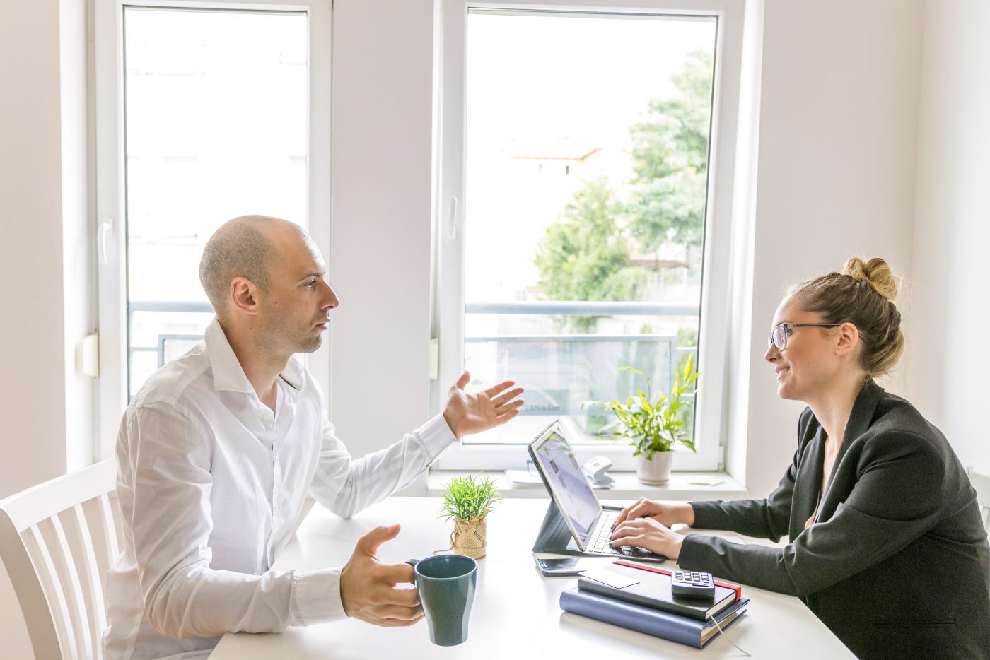 Two colleagues in conversation across a desk in an office