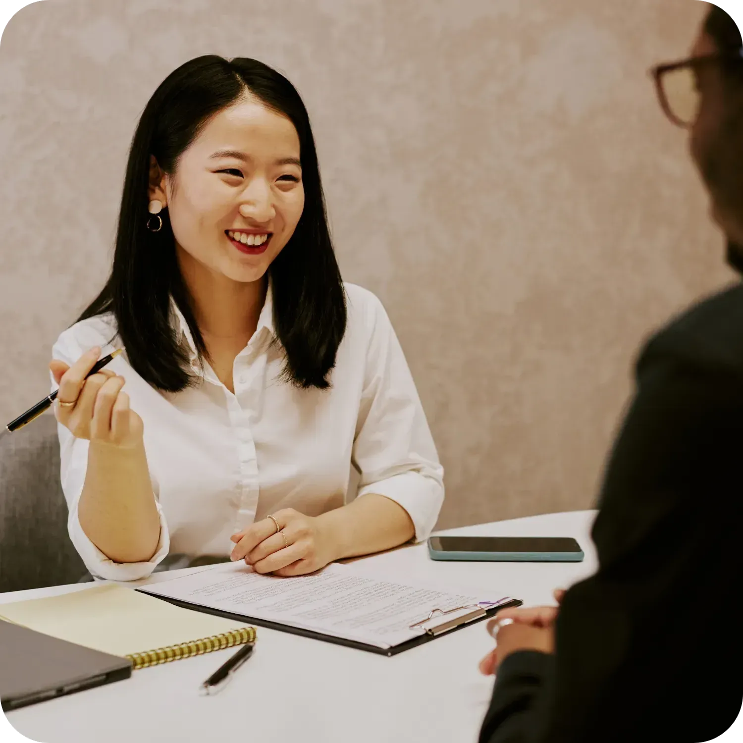 Woman in white blouse smiling during a meeting at a table.