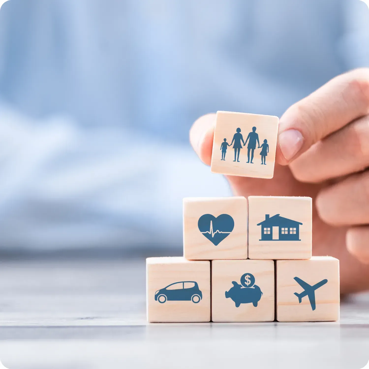 Wooden blocks with icons: family, heart, house, car, piggy bank, and airplane.
