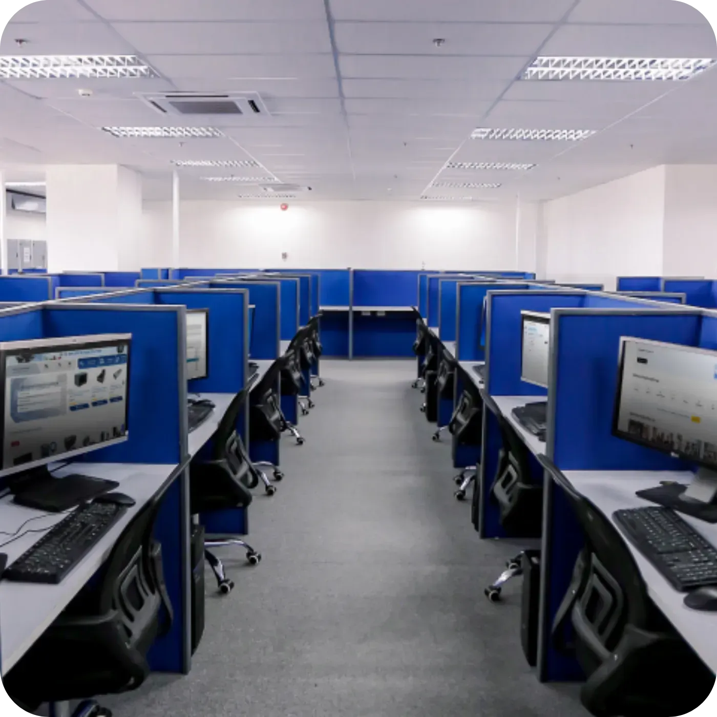 Modern office space with rows of blue cubicles and computers.