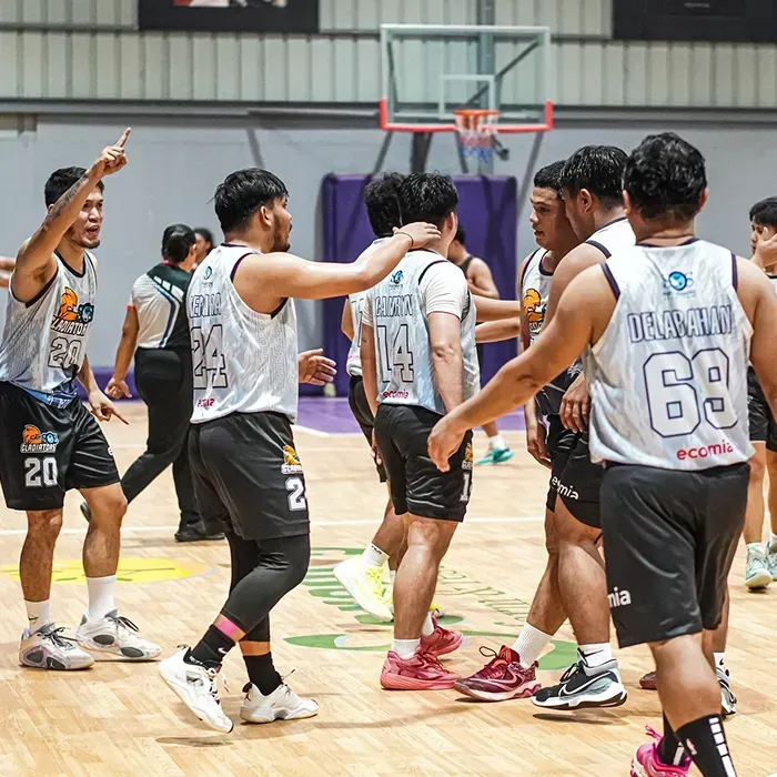 Basketball team celebrating on court with high-fives and smiles.