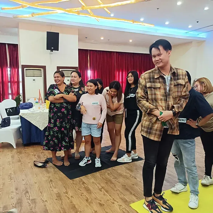 People in a room, standing in groups, smiling and interacting.
