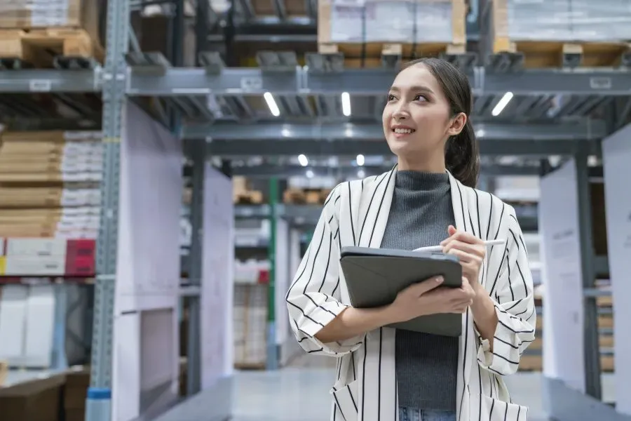 Warehouse manager checking stock on shelves against a tablet